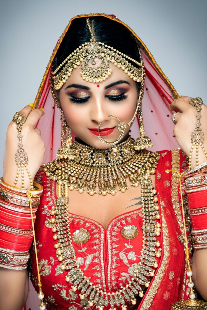 Home A stunning Indian bride adorned in traditional jewelry and vibrant red attire, showcasing elegance.