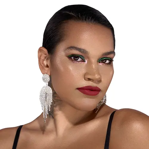 Model with editorial makeup by Roque Cozzette featuring bold red lips, glowing skin, and blended purple eyeshadow, photographed for Cozzette Beauty