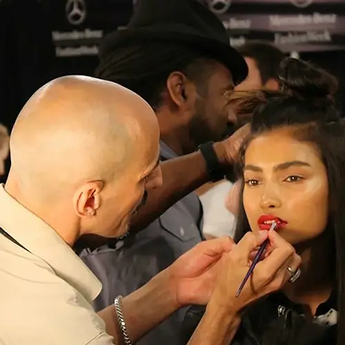 Roque Cozzette applying red lipstick backstage at New York Fashion Week for the Reem Acra show using Cozzette Beauty products
